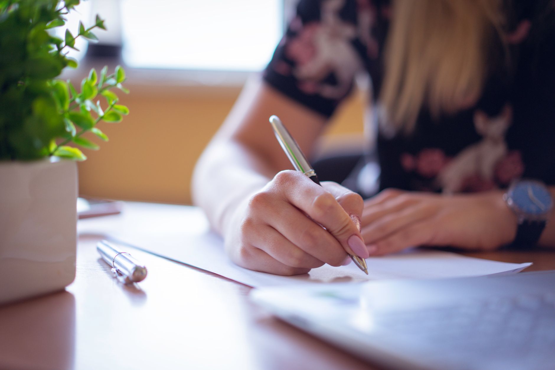 Main écrivant sur un document, à un bureau