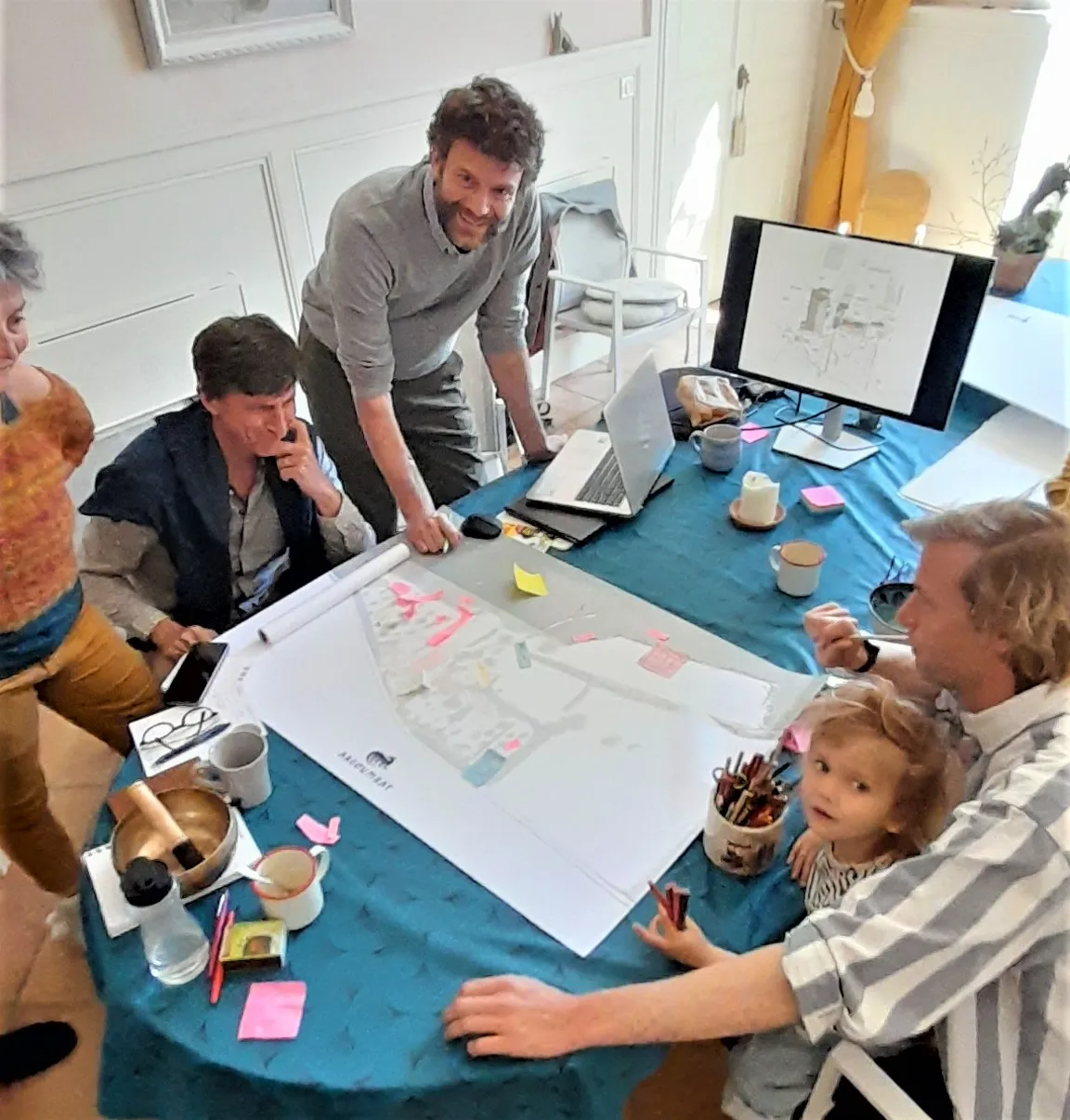 Travail en groupe autour du plan d’ensemble de l’écolieu d’Argoumbat, posé sur une table et annoté de papillons adhésifs