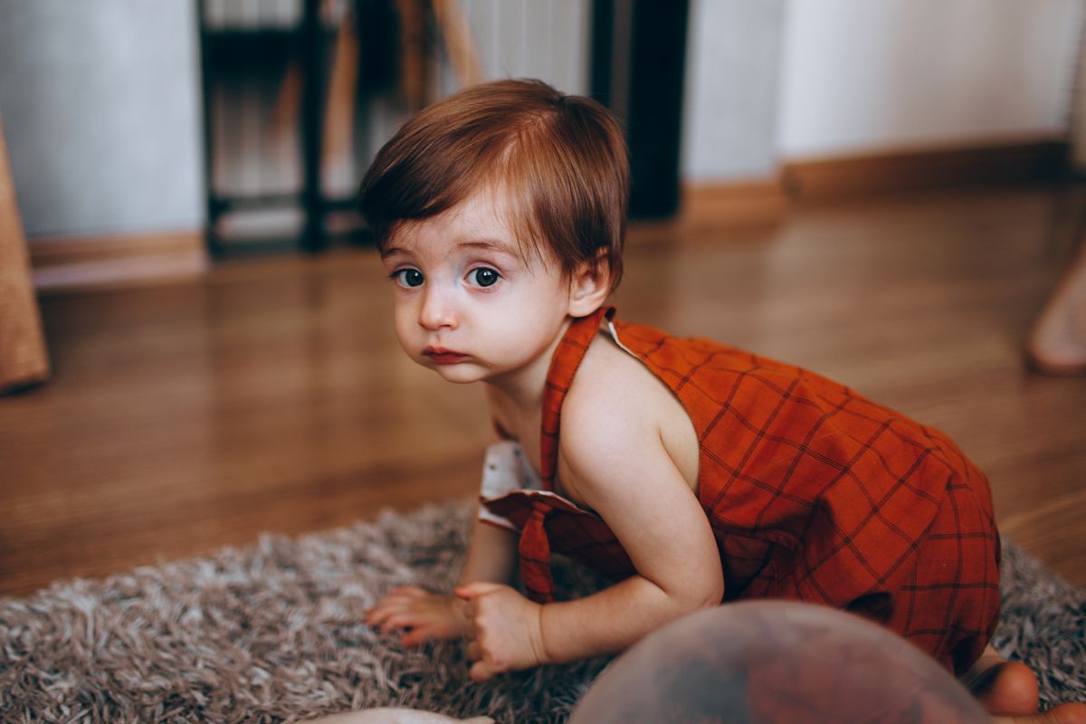 Un bébé se déplace à quatre pattes sur un tapis, une étape clé du développement moteur.