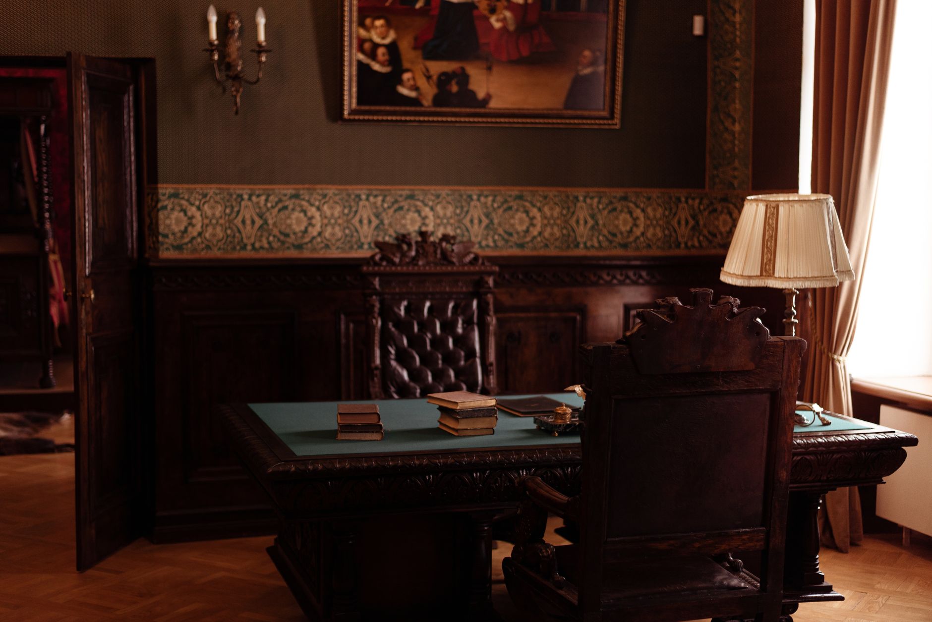 Bureau de travail ancien en bois sculpté, livres et lampe, dans un cabinet feutré